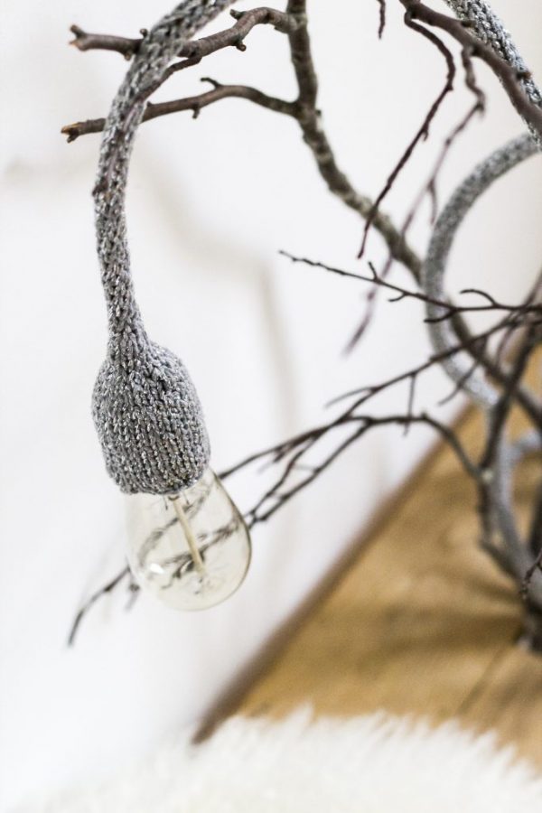 lampe baladeuse gris argenté disposée sur une branche d'arbre
